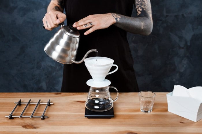 Mann bereitet Kaffee mit Coffee Dripper zu