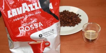 Qualita Rossa von Lavazza Kaffeeverpackung offen mit Kaffeebohnen auf Teller und Kaffee