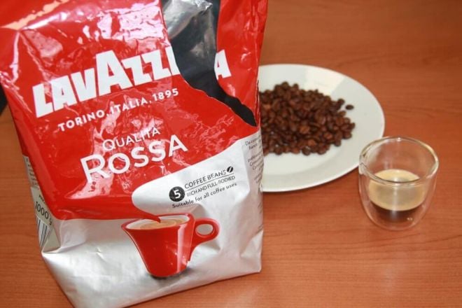 Qualita Rossa von Lavazza Kaffeeverpackung offen mit Kaffeebohnen auf Teller und Kaffee