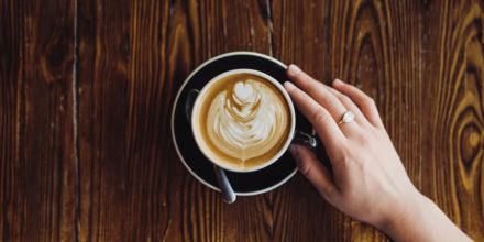 Latte-Art-Frau-hält-Tasse