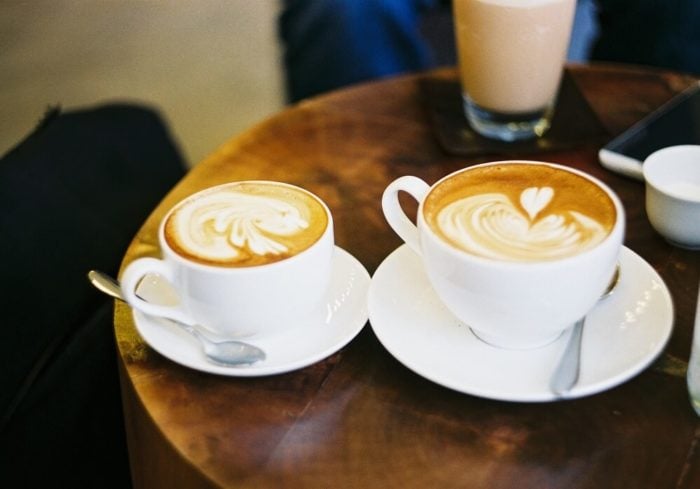 zwei-kaffeetassen-auf-tisch-latte-art-herz