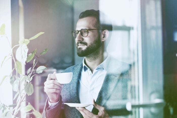 Mann trinkt Kaffee hinter Fenster