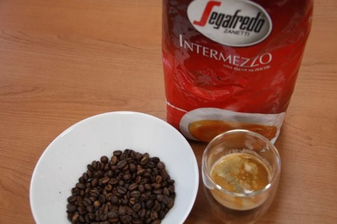 Segafredo Intermezzo Verpackung neben Bohnen und frisch zubereitetem Kaffee