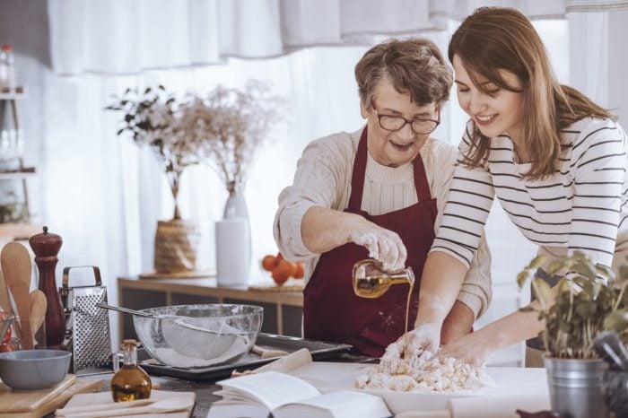 Ältere und jüngere Damen kneten einen Teig