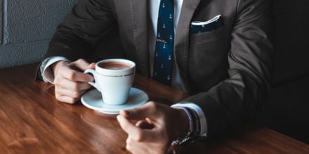 Mann im Anzug hält Kaffee in der Hand