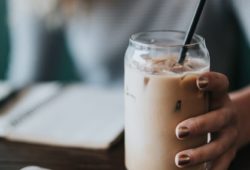 Frau hält Glas mit Eiskaffee in der Hand