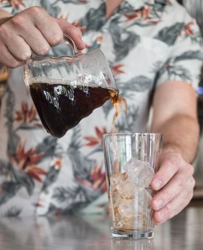Cold Brew Kaffee wird in Glas mit Eiswürfeln gegossen