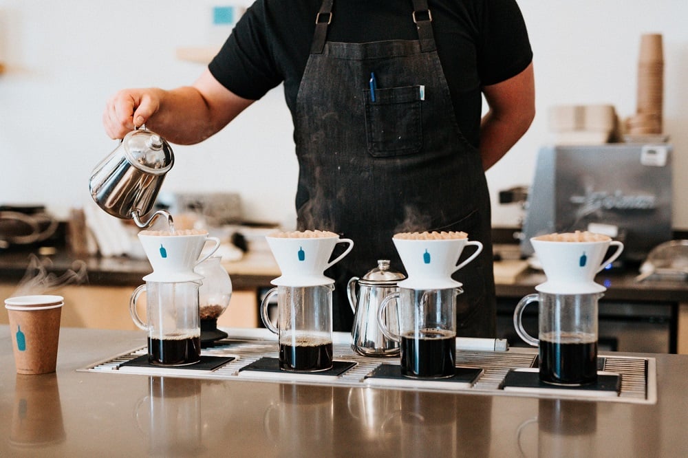 Mann bereitet vier Filterkaffees zu