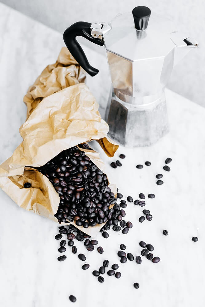 Espressokocher neben Kaffeebohnen