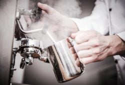 Barista schäumt Milch auf