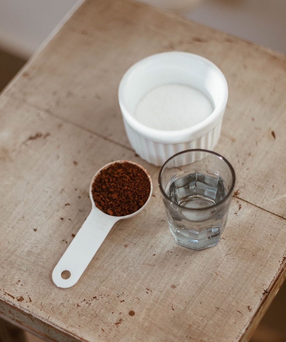 Instant-Kaffee Pulver mit Glas Wasser und Zucker
