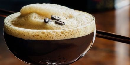 Espresso Martini in Glas mit Espressobohnen auf Schaum quer