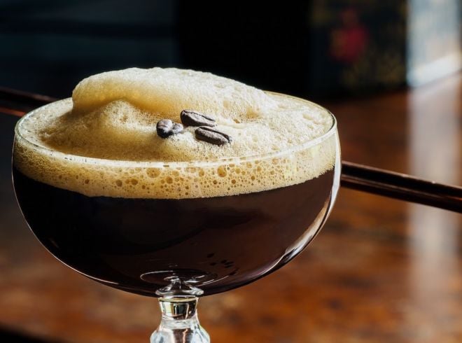 Espresso Martini in Glas mit Espressobohnen auf Schaum quer