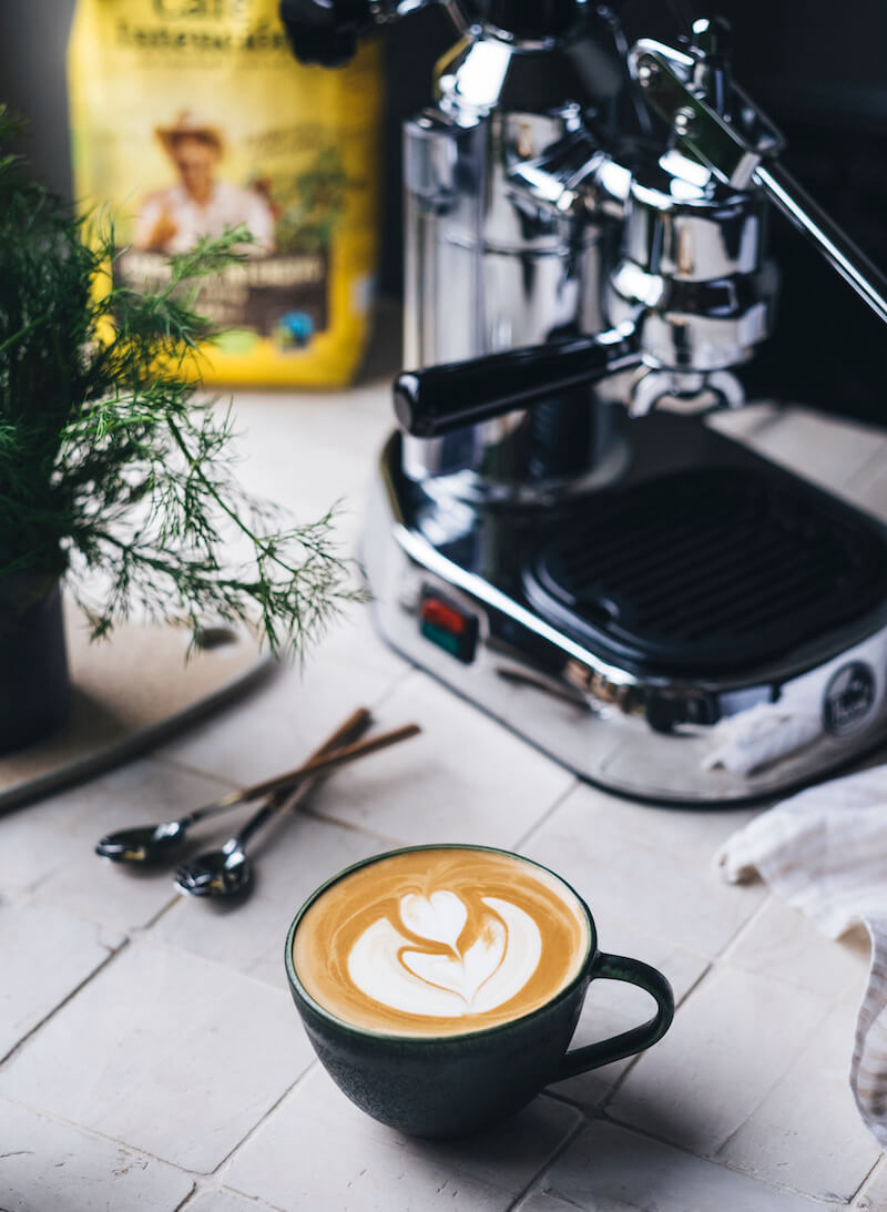 Café Intención Kaffee neben Siebträgermaschine und Cappuccino